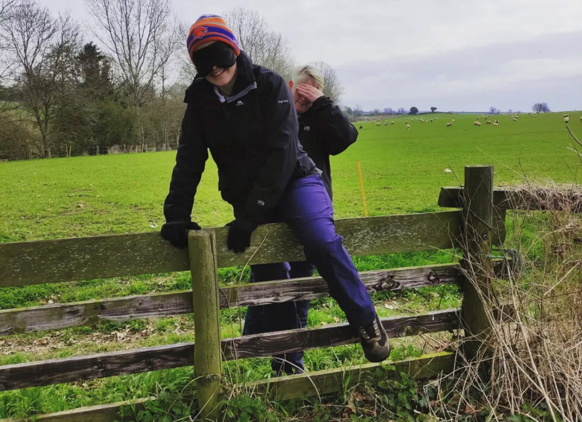Abbie climbing over a wooden fence with a blindfold in training for her Blind Trek up Snowdon